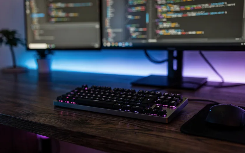 Utvecklingsmiljö med kod på skärmar och tangentbord på skrivbord